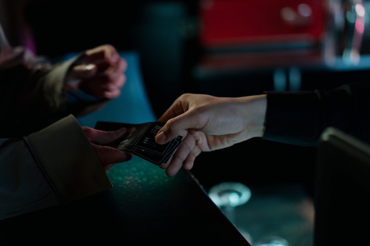 Hands exchanging tickets indoors at a venue counter