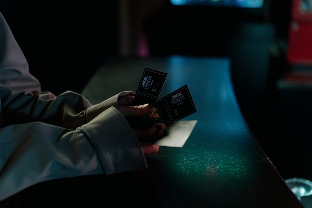 Close-up of hands holding concert tickets at a counter
