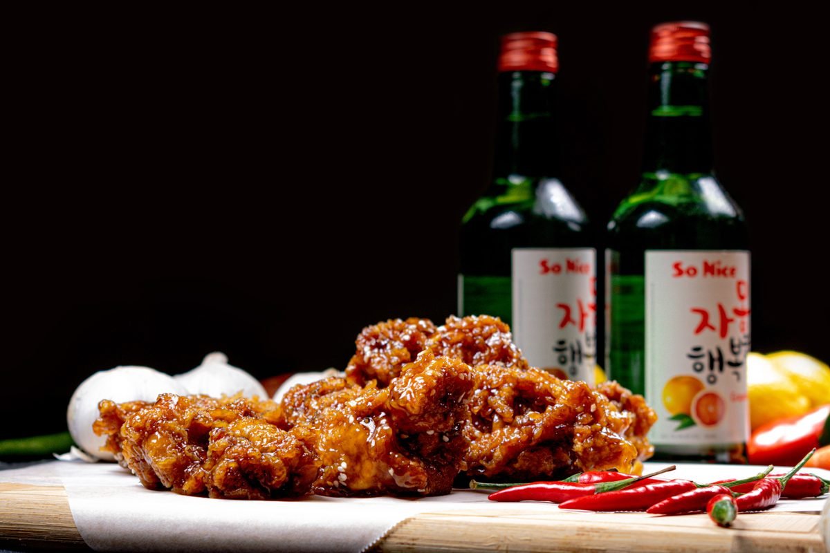 Crispy Korean fried chicken and bottles of soju on a table