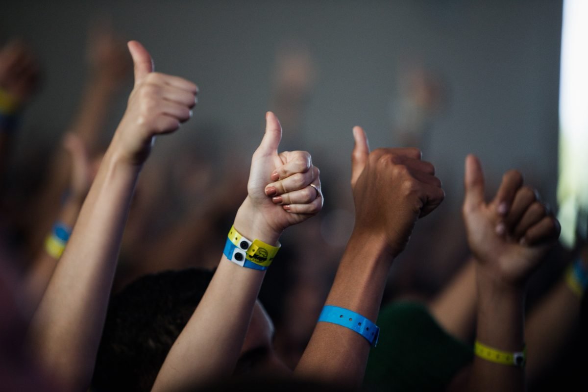 Diverse hands giving thumbs up with colorful festival wristbands