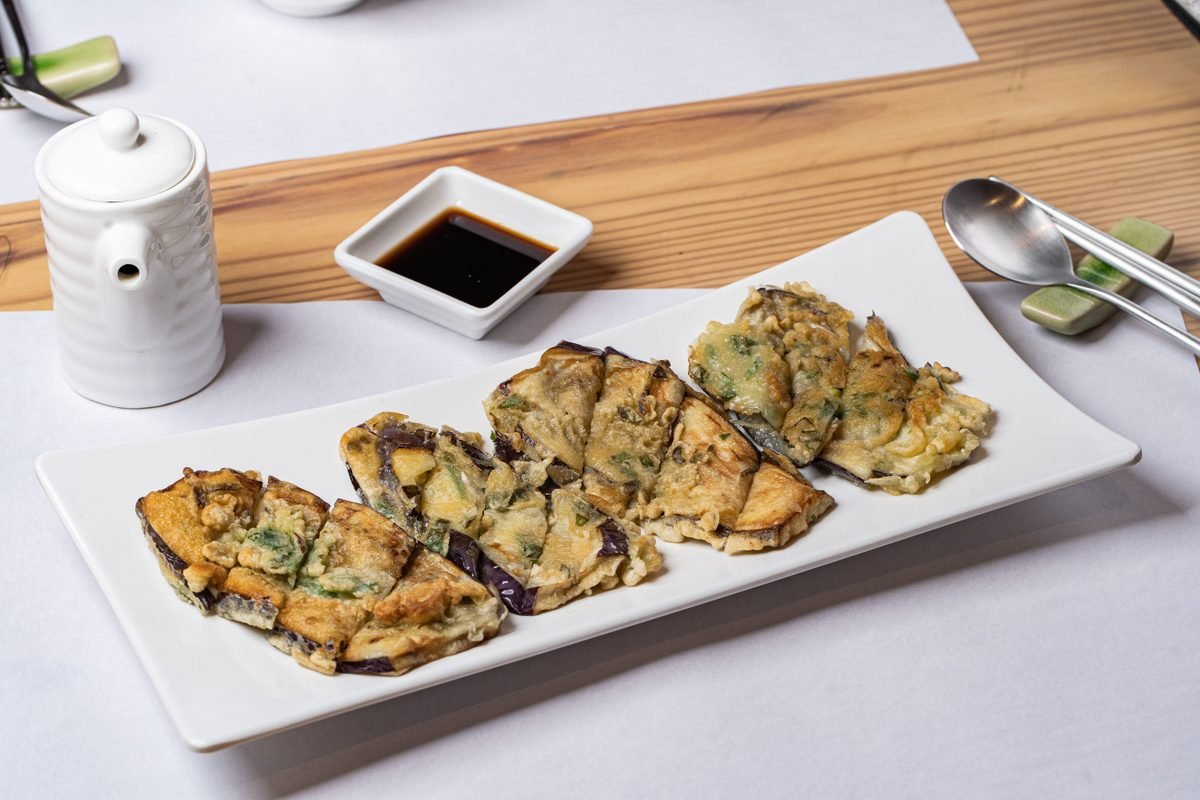 Fried pancake slices served with soy sauce on a white plate