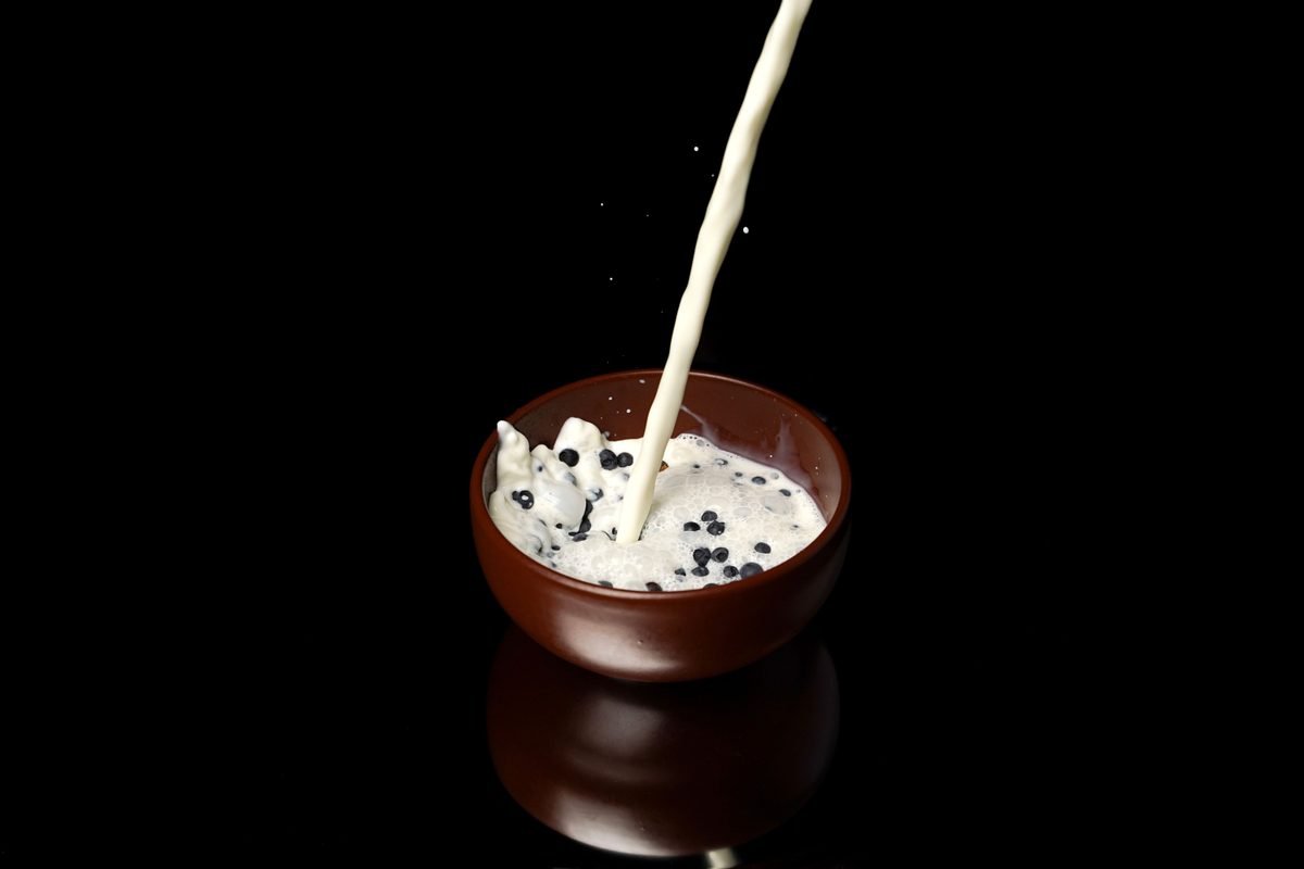 Milk pouring into a small bowl with dark pieces