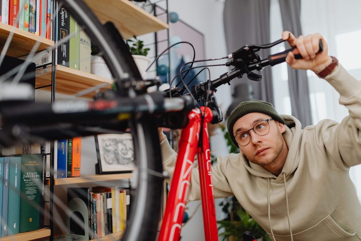 A man focused on repairing bicycle handlebars indoors.