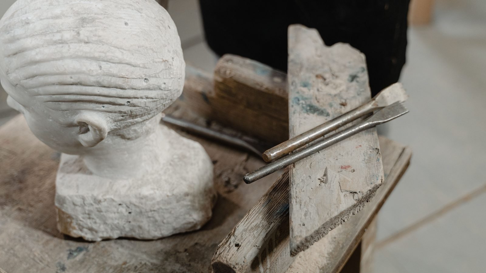 Marble sculpture head with chiseling tools on a wooden table in an artist studio