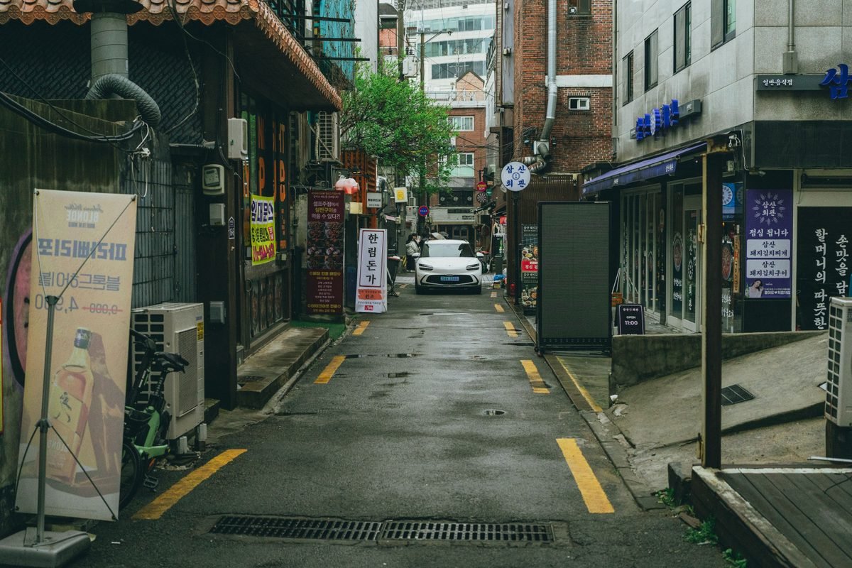 Narrow alleyway in Seoul with traditional Korean signage and parked car.