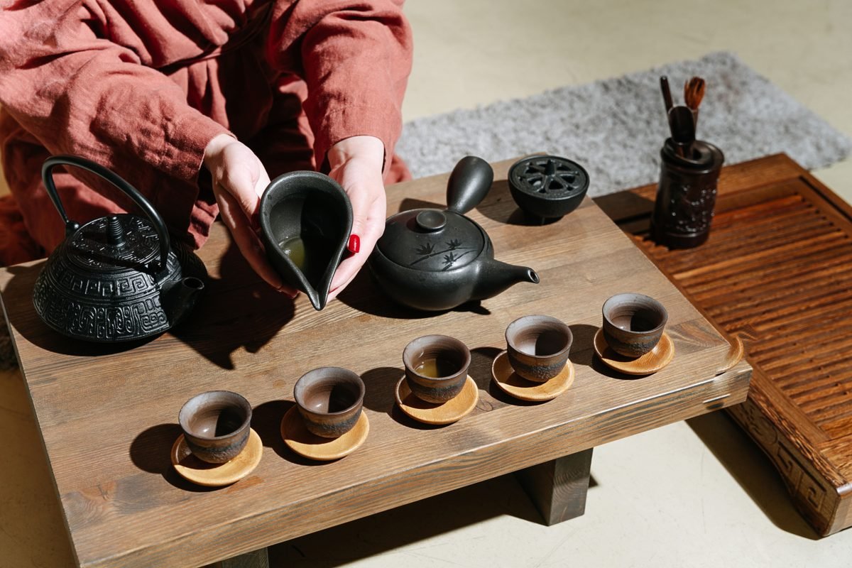 A person pouring tea at a wooden table during a ceremony