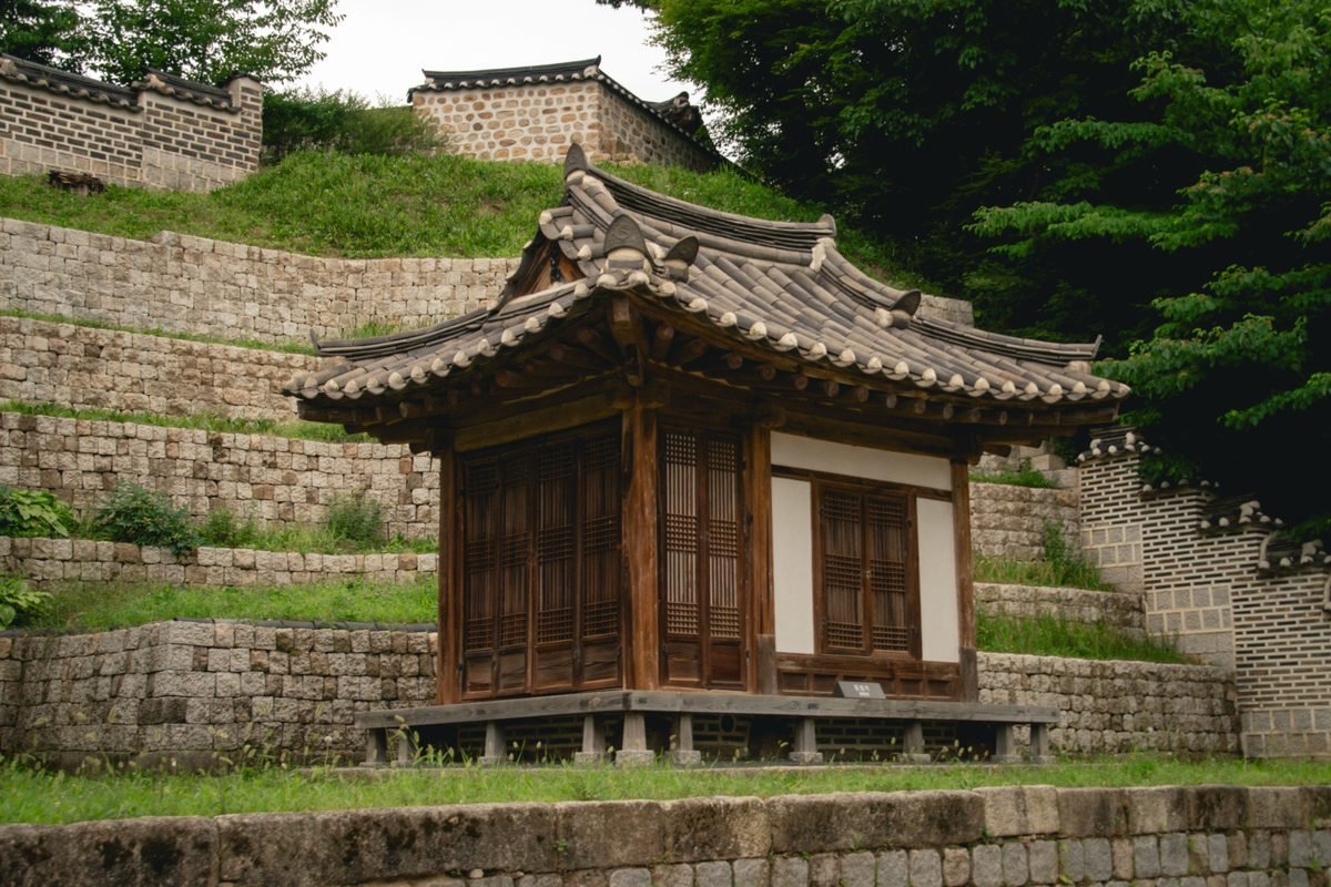 Traditional wooden pavilion set against stone terraces in Seoul