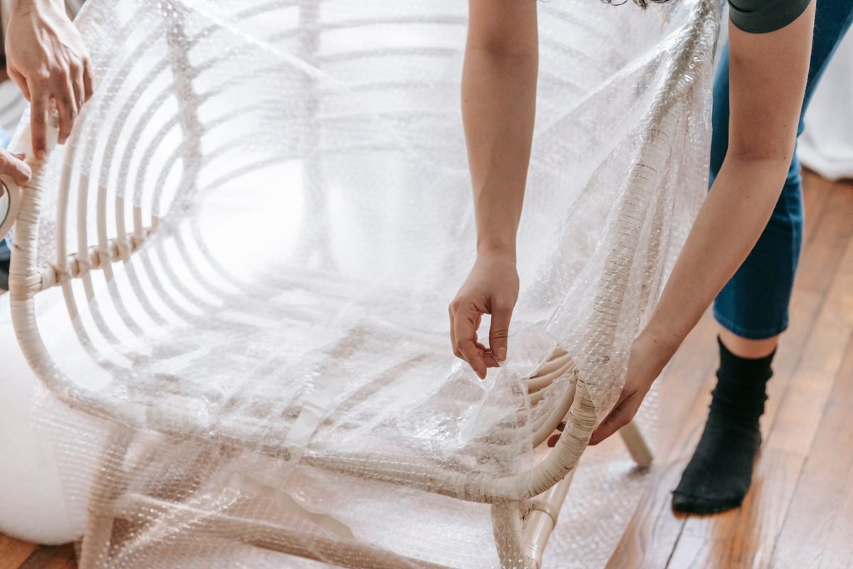 Person wrapping a wooden furniture chair carefully in bubble wrap