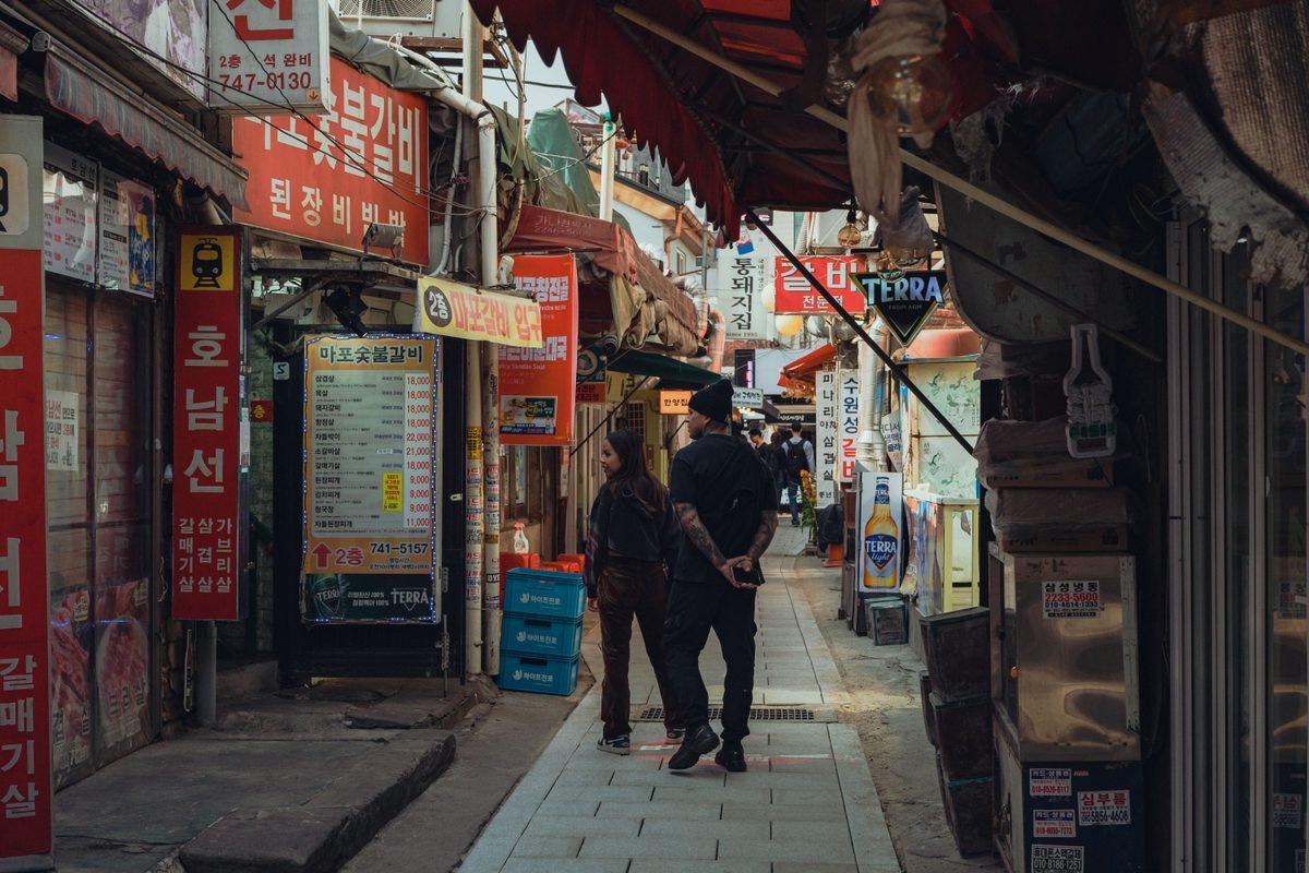 A narrow alleyway at Hwanghak-dong Flea Market in Seoul lined with shops and signs