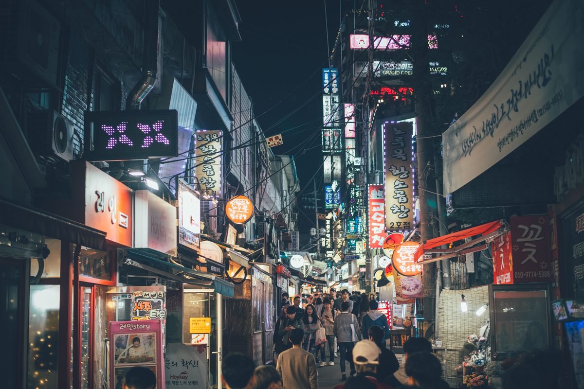 Bustling night market street in Seoul with neon lights and crowds