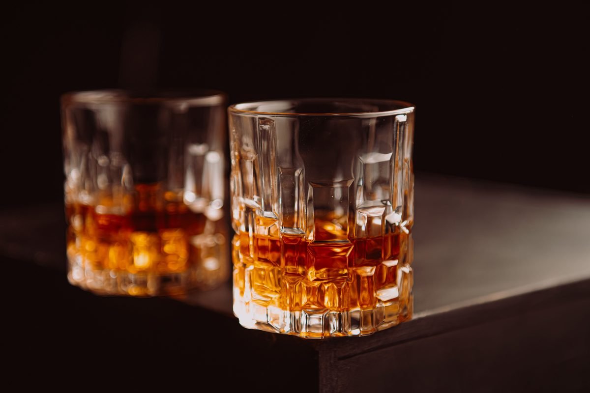Crystal glasses filled with whiskey on a dark wooden surface