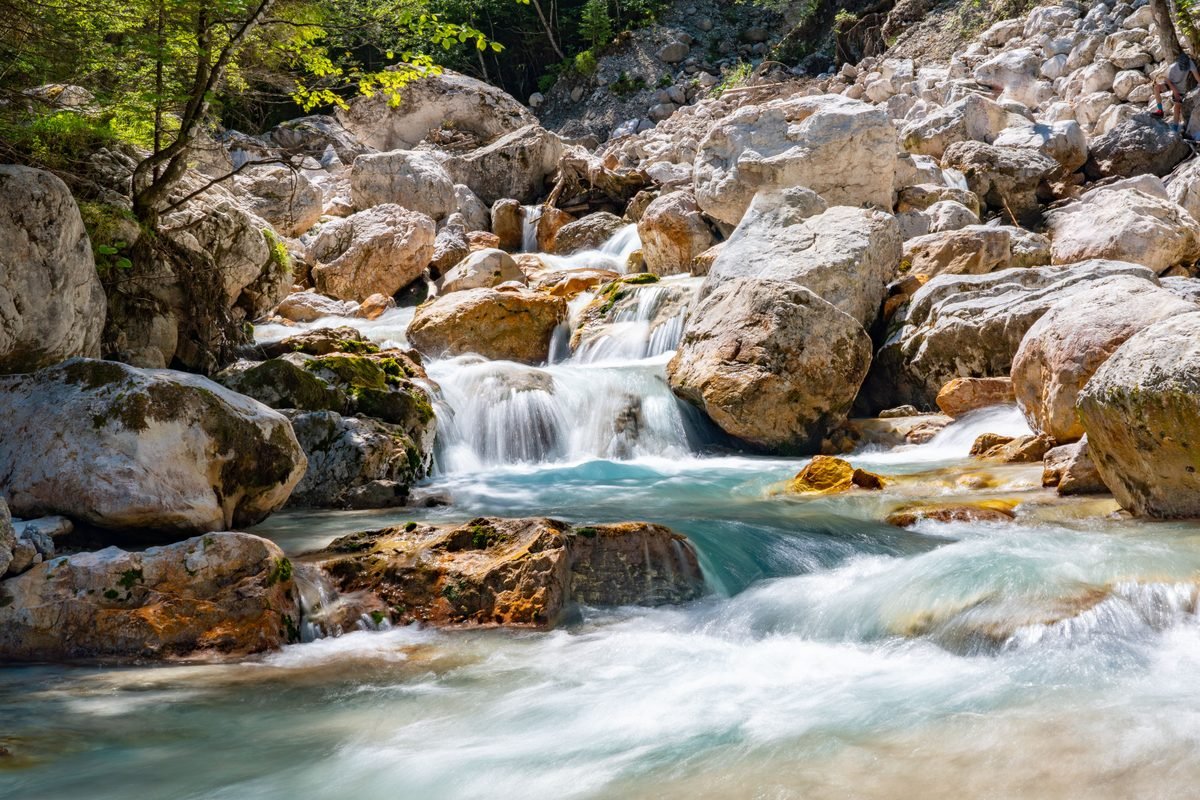 Rushing mountain creek cascading over smooth rocks in a lush forest setting.
