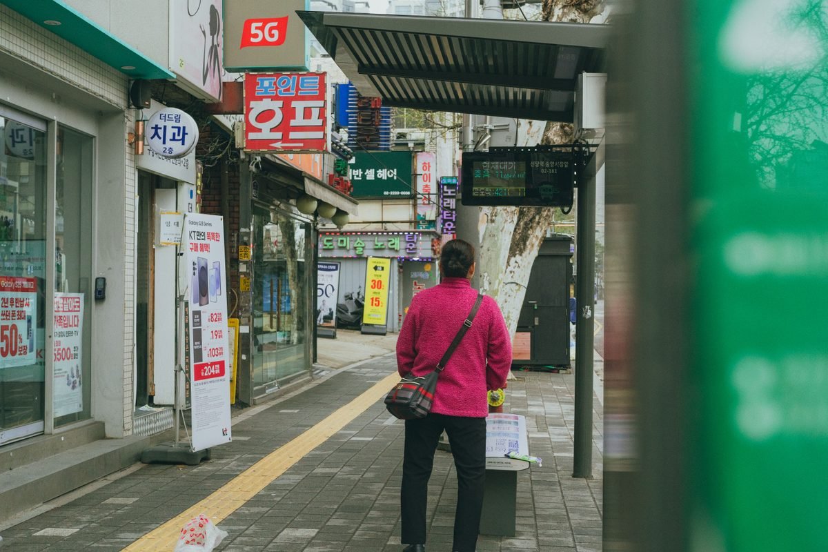 Person waiting at a bus stop in Seoul, South Korea with street signage.