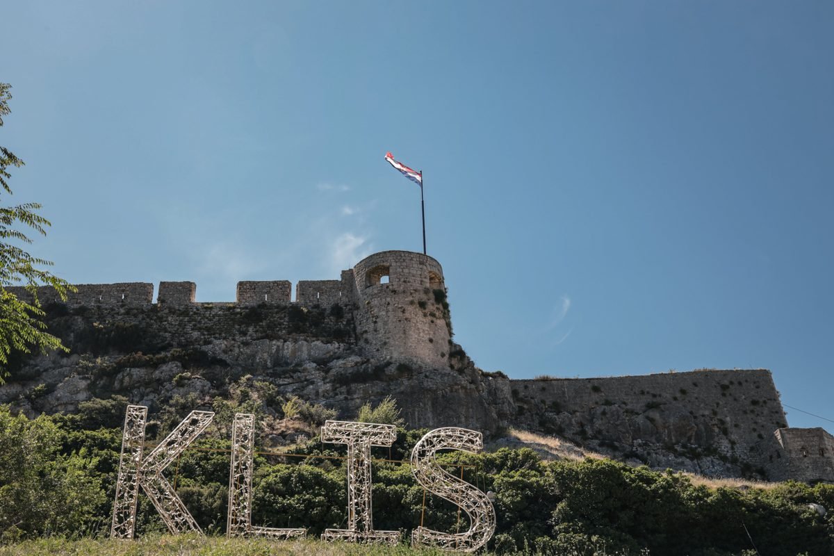 Stone fortification walls with a Croatian flag flying at Klis Fortress