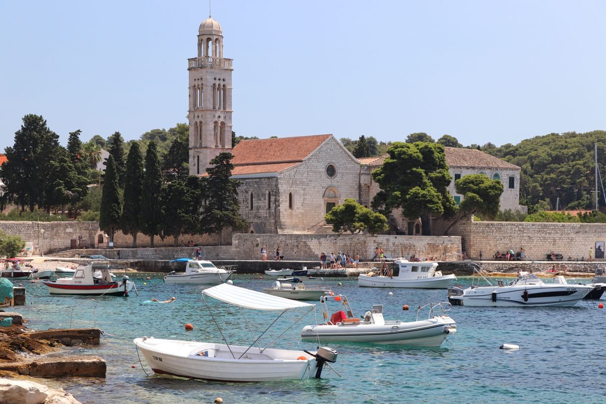Coastal village harbor with small moored boats and a historic church tower