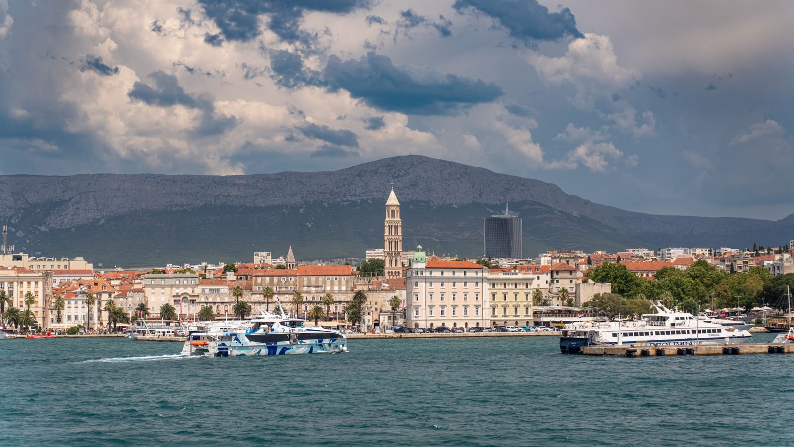 Catamaran operating near the Split waterfront with the bell tower in background