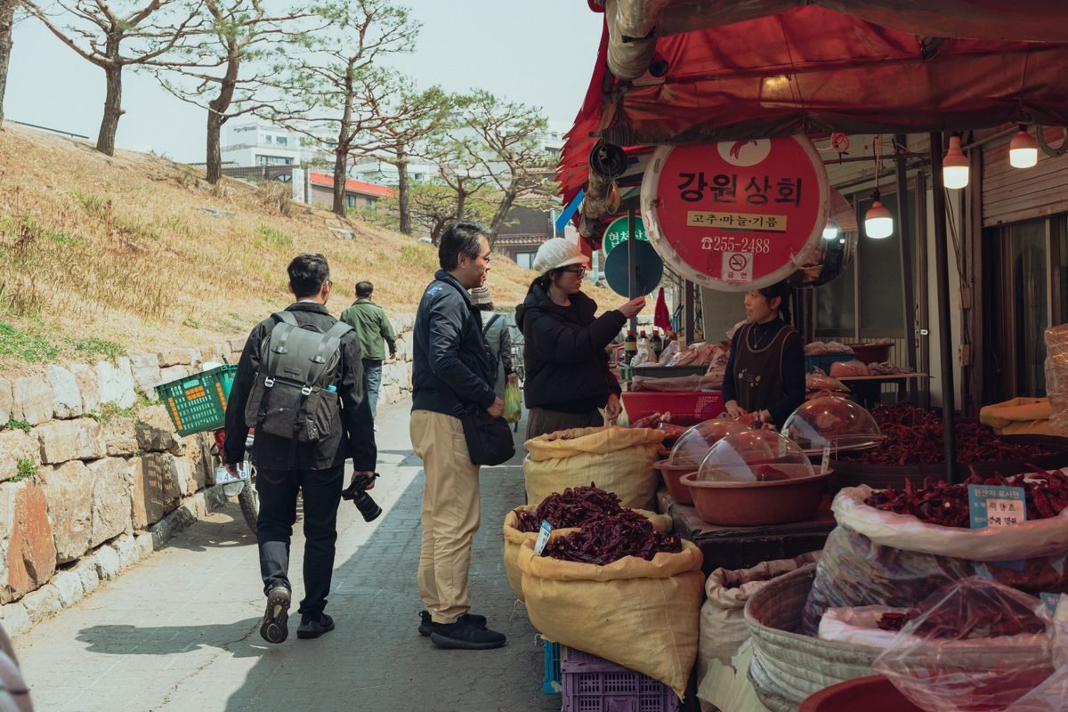 Outdoor market stall displaying sacks of grains and red peppers