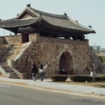 Hwaseong Fortress stone gate with traditional tiled roof under clear skies in Suwon