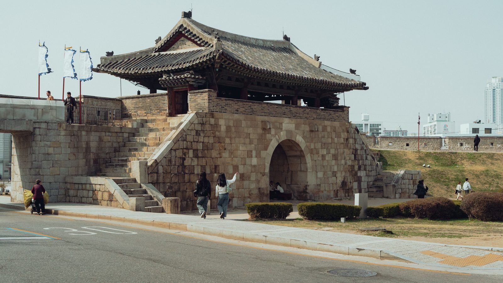 Hwaseong Fortress stone gate with traditional tiled roof under clear skies in Suwon