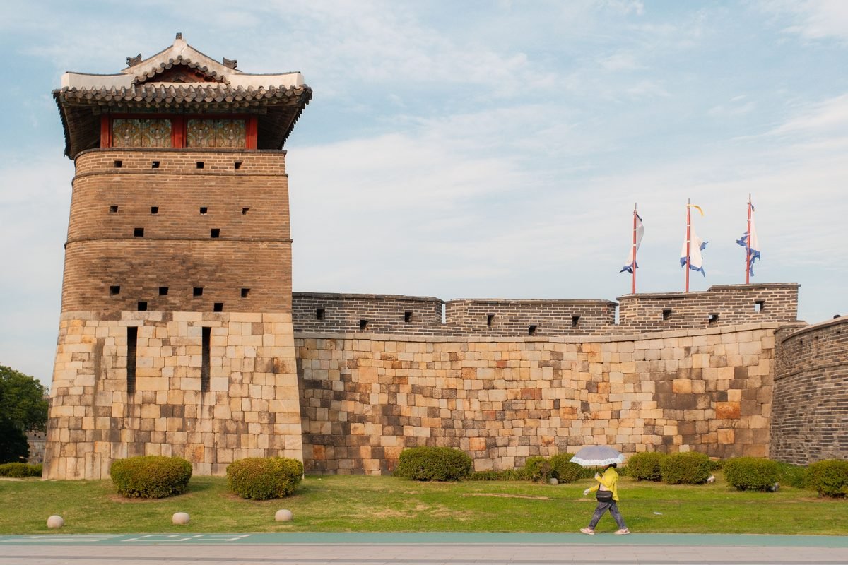 Person walking past the historic Suwon Hwaseong Fortress