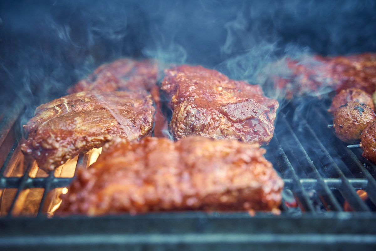 Thick barbecue meat sizzling and smoking on a grill