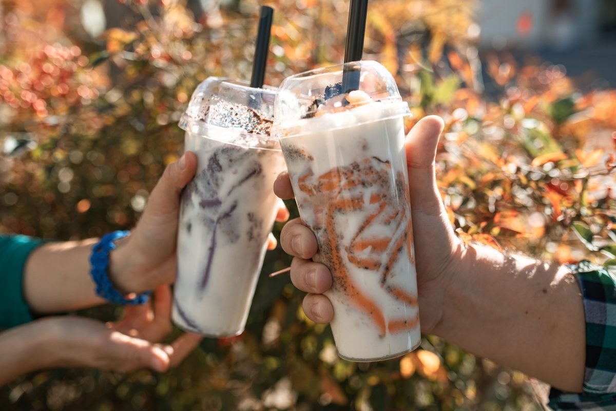 Two people holding colorful bubble teas outdoors