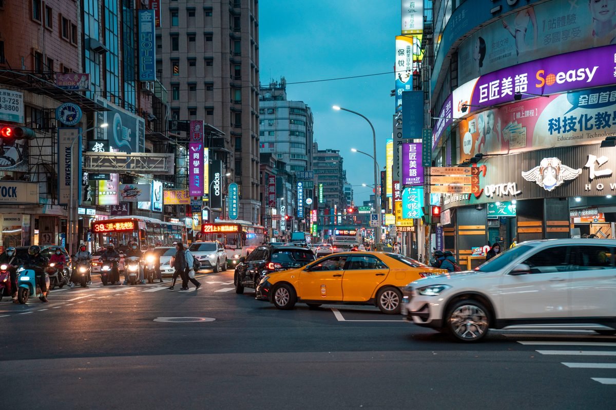 Vibrant street scene in Taipei with illuminated commercial signs and traffic.