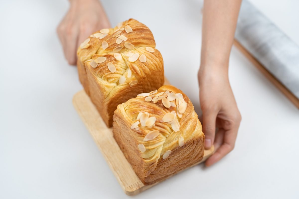 Freshly baked almond-topped pastries on a wooden tray