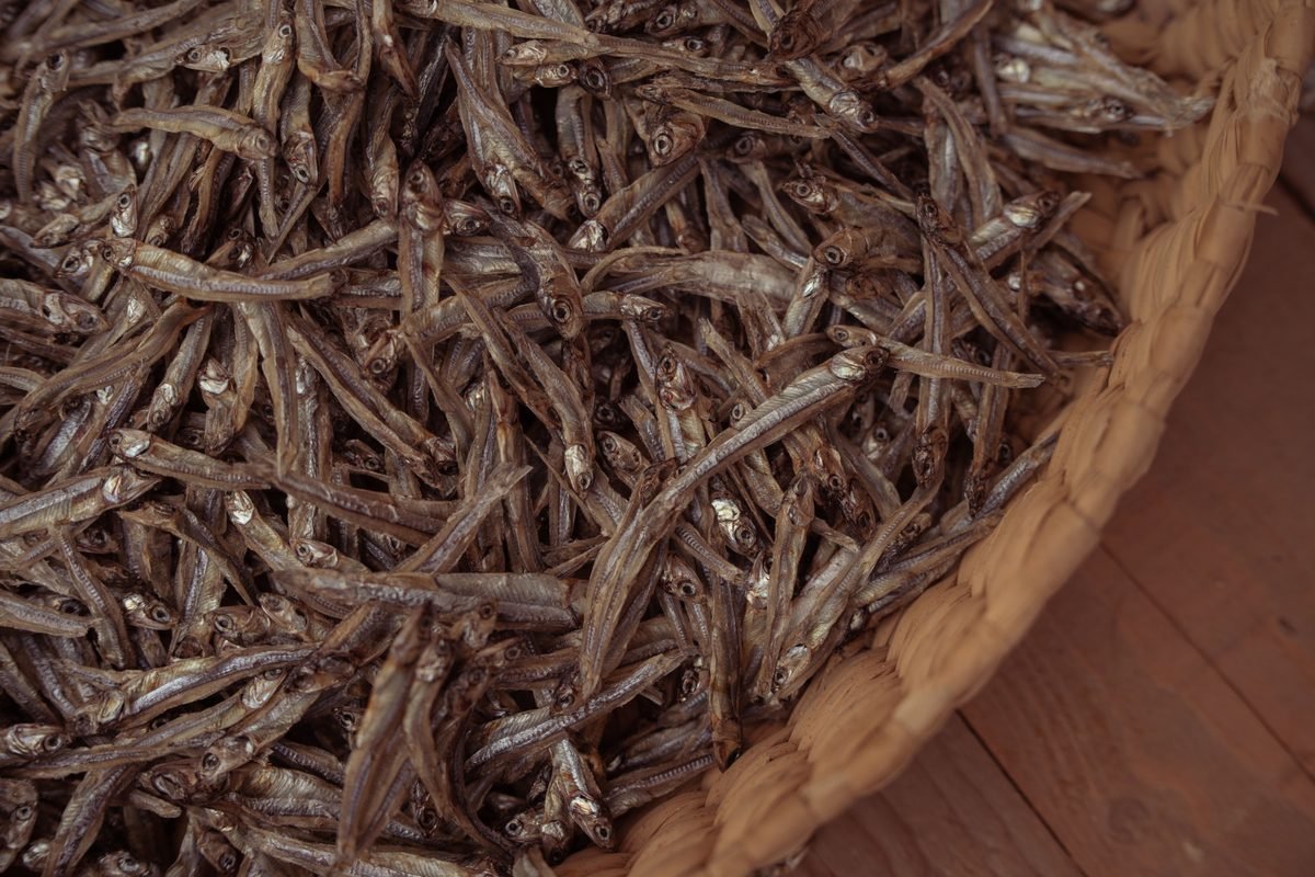A large woven basket filled with dried anchovies.
