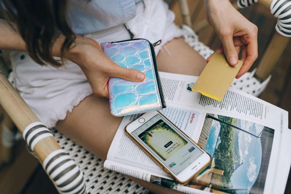 Woman holding smartphone and credit card with wallet.