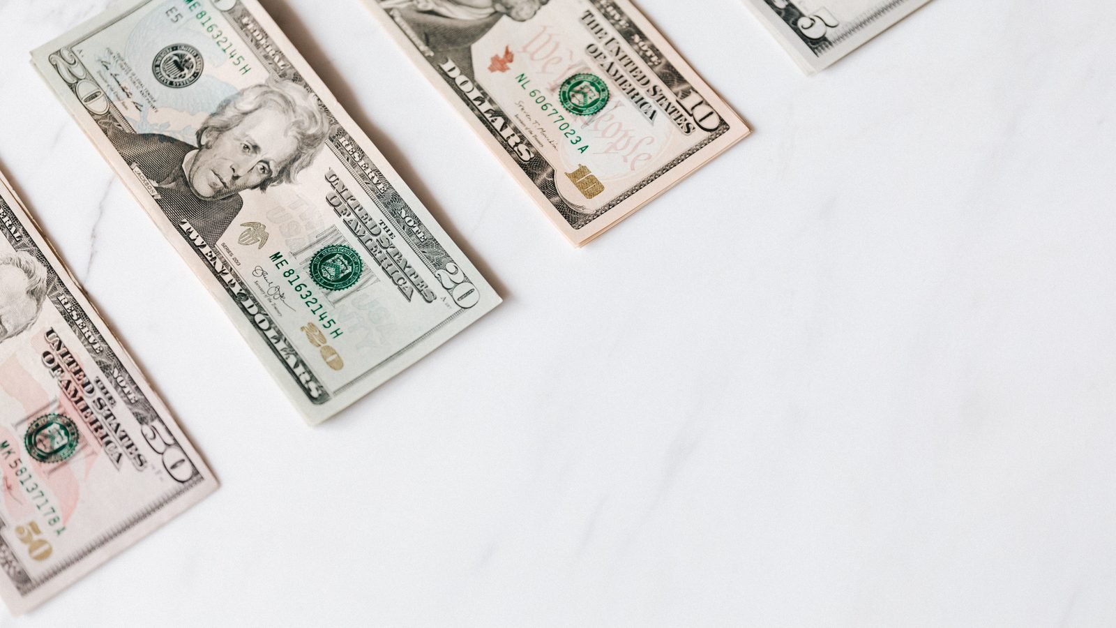 US dollar banknotes in different denominations in a row.