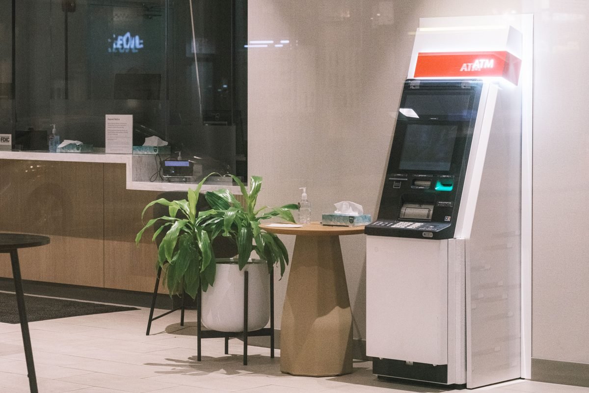 An ATM machine standing in a modern bank lobby.