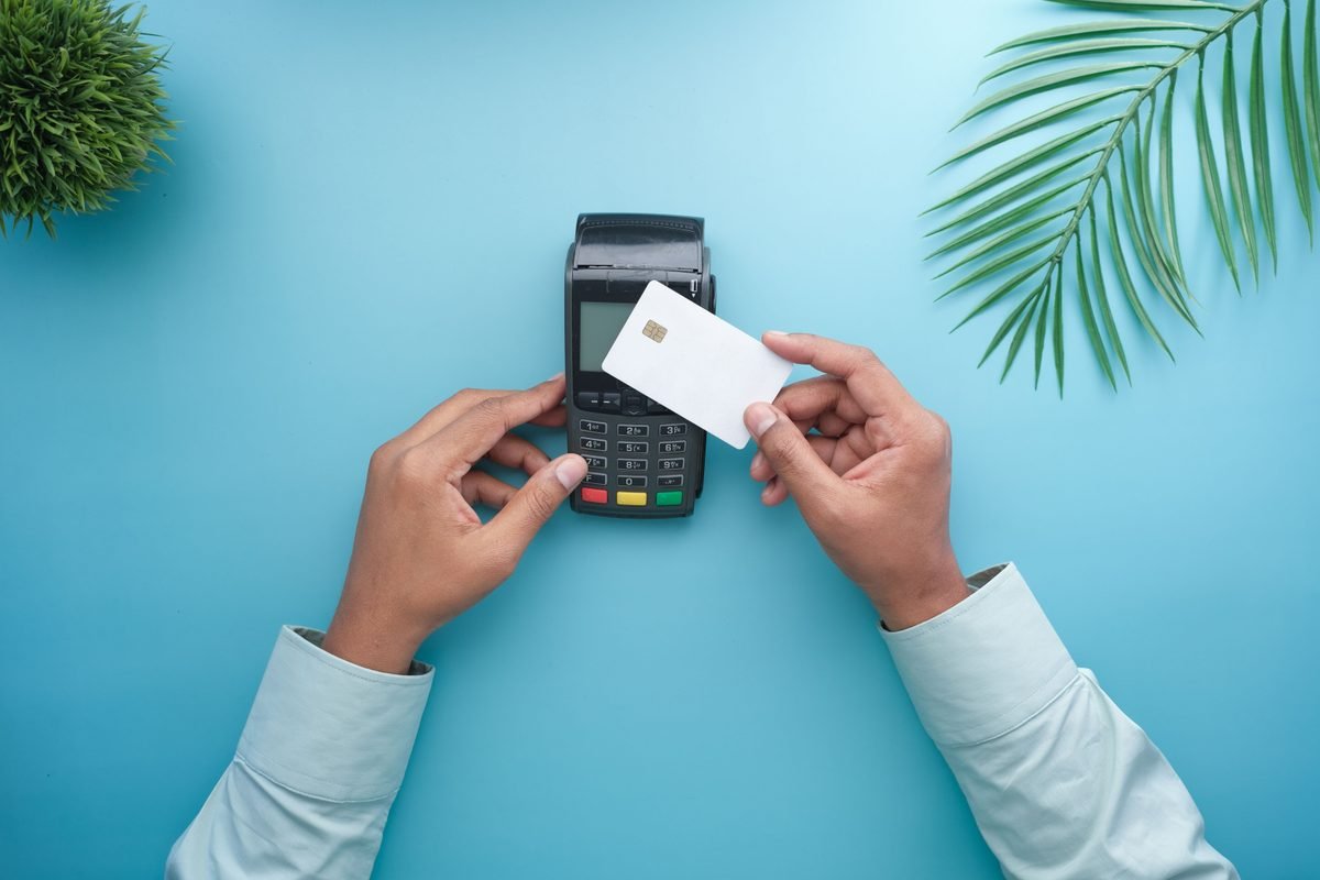 Hands using a contactless credit card on a payment terminal.