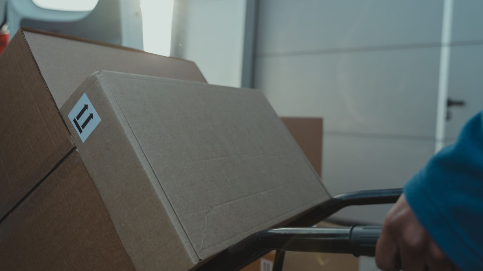 A cardboard shipping box on a trolley inside a van.
