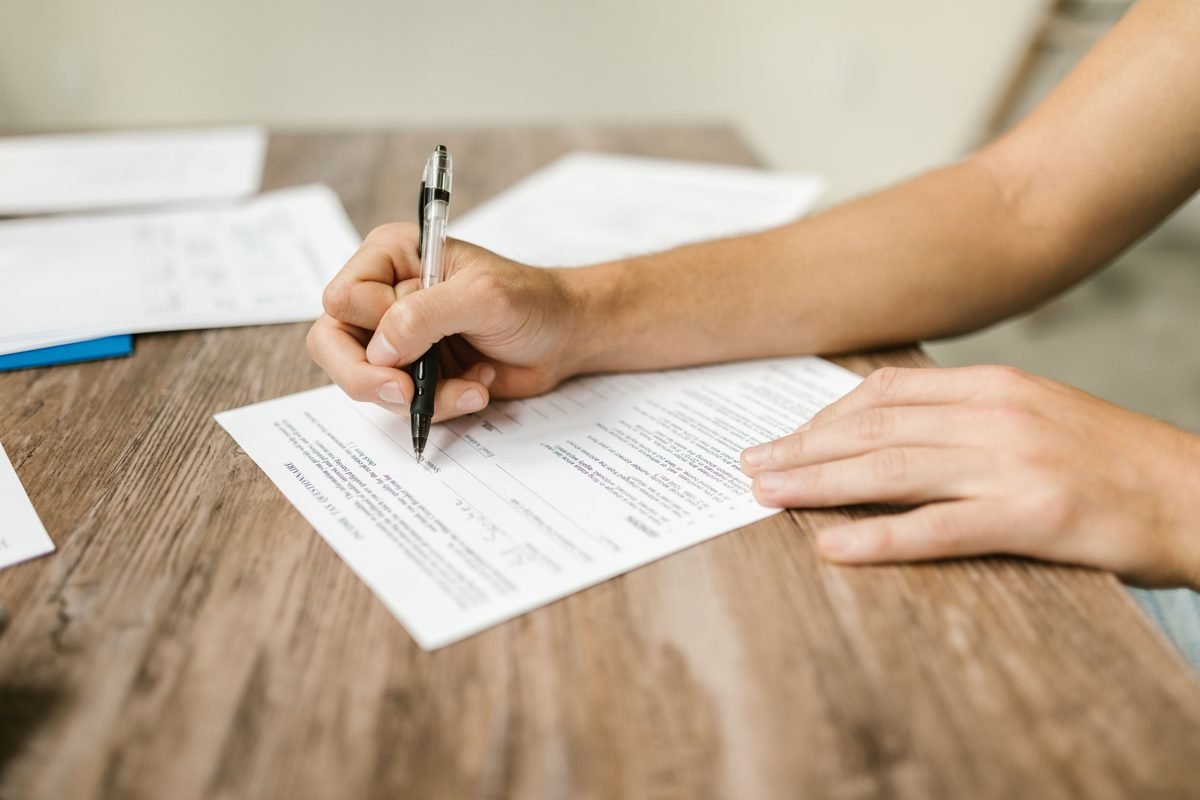 A person filling out a form with a pen.