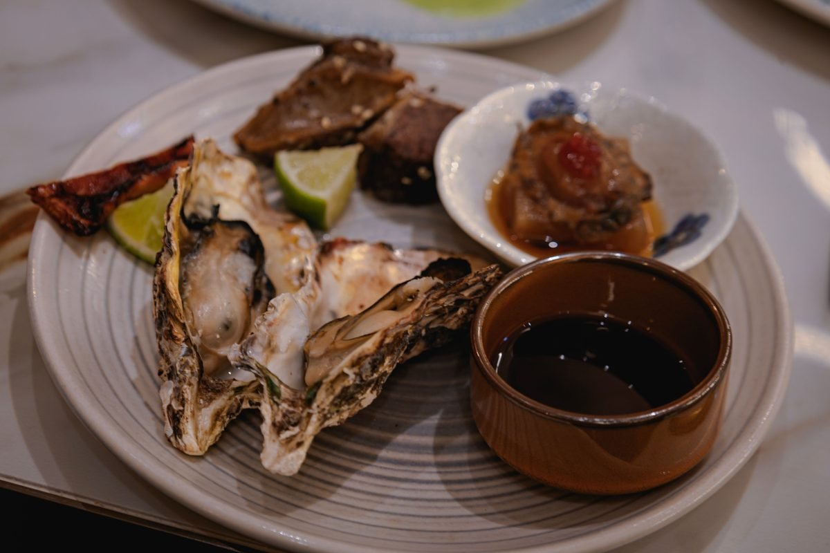 A gourmet plate featuring fresh oysters, lime, and dipping sauce.