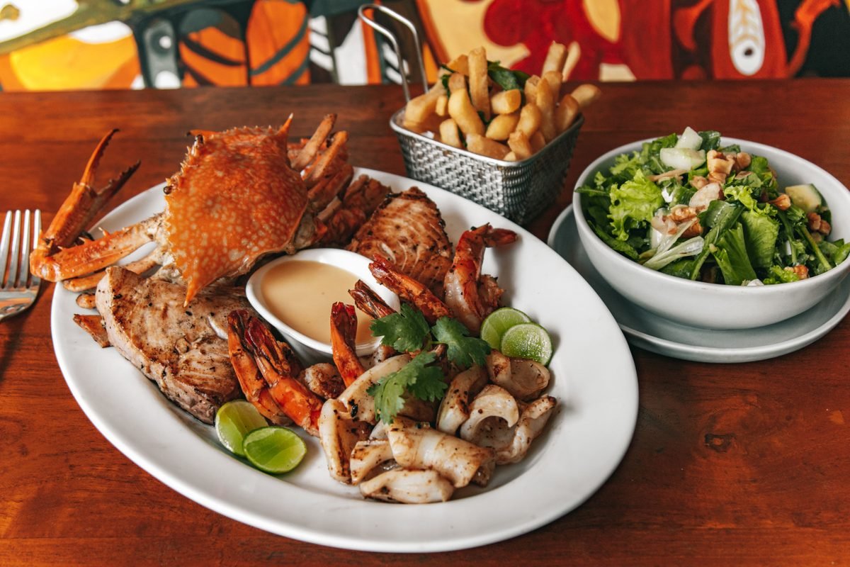 A large seafood platter with crab, shrimp, squid, salad, and fries.
